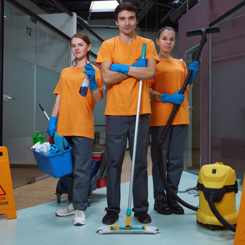 Cleaning company workers holding necessary housecleaning equipment