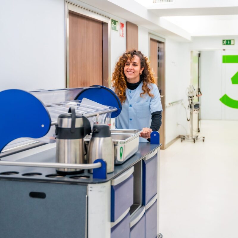 Nurse carrying coffee with a trolley along hospital